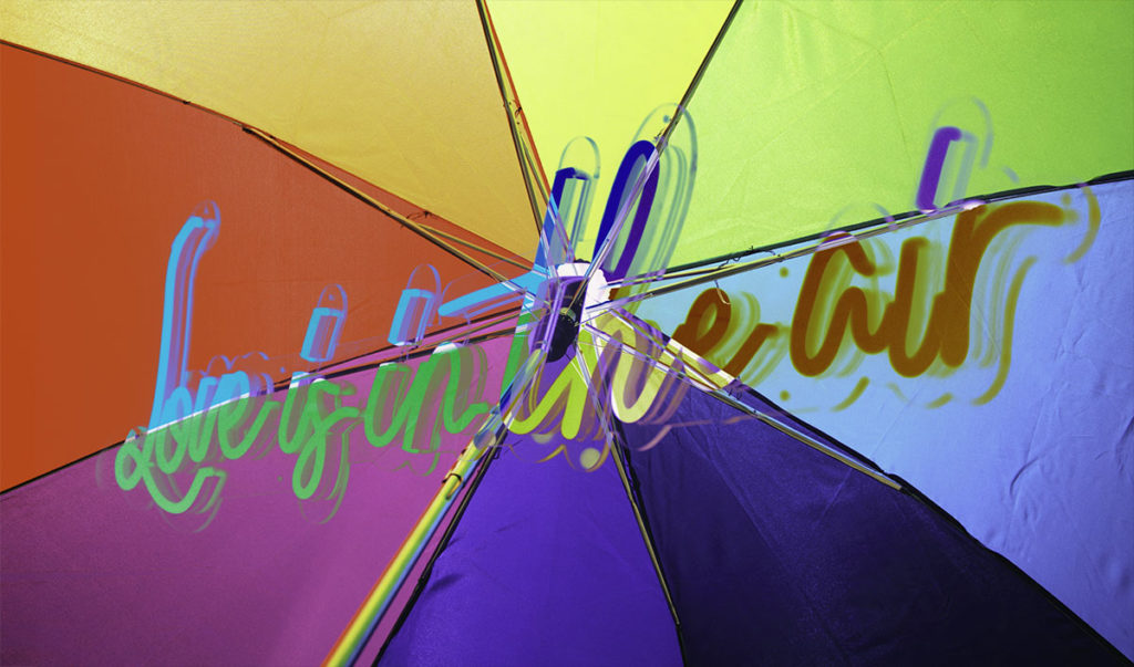 Pan Means Pan - Falling In Love with the Universe 5 text 'Love is in the Air' superimposed on rainbow umbrella used for article 'Pan Means Pan - Falling In Love with the Universe'