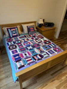 More than Fragments - a photo of the quilt on a bed.